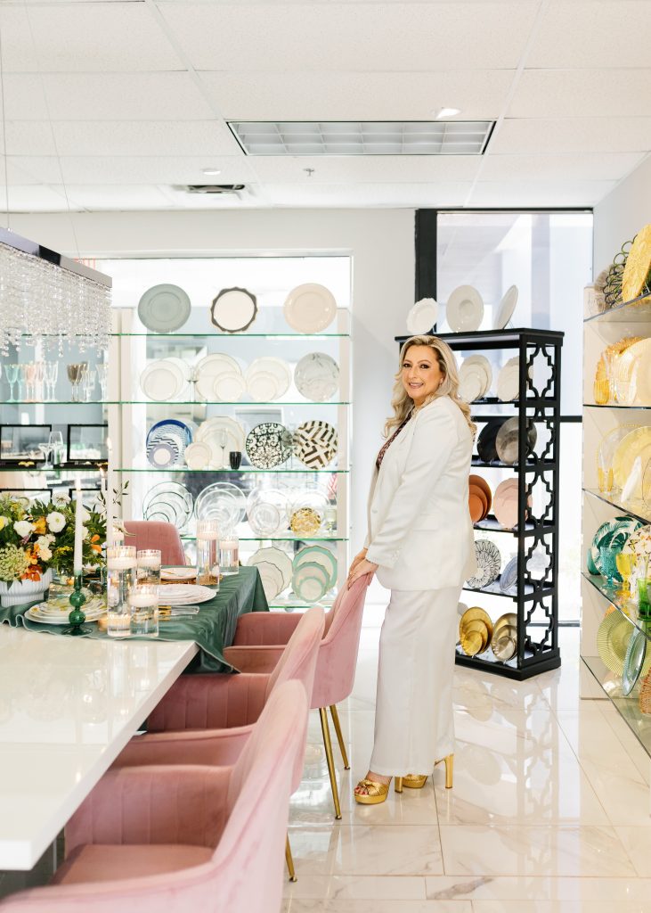 a founder and CEO of Different Look Rentals in a white suit standing next to a table with plates