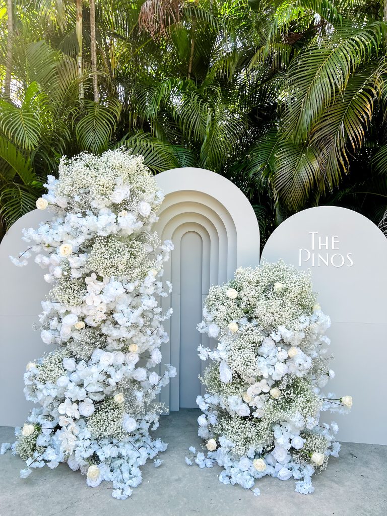 a white arch with flowers and a sign