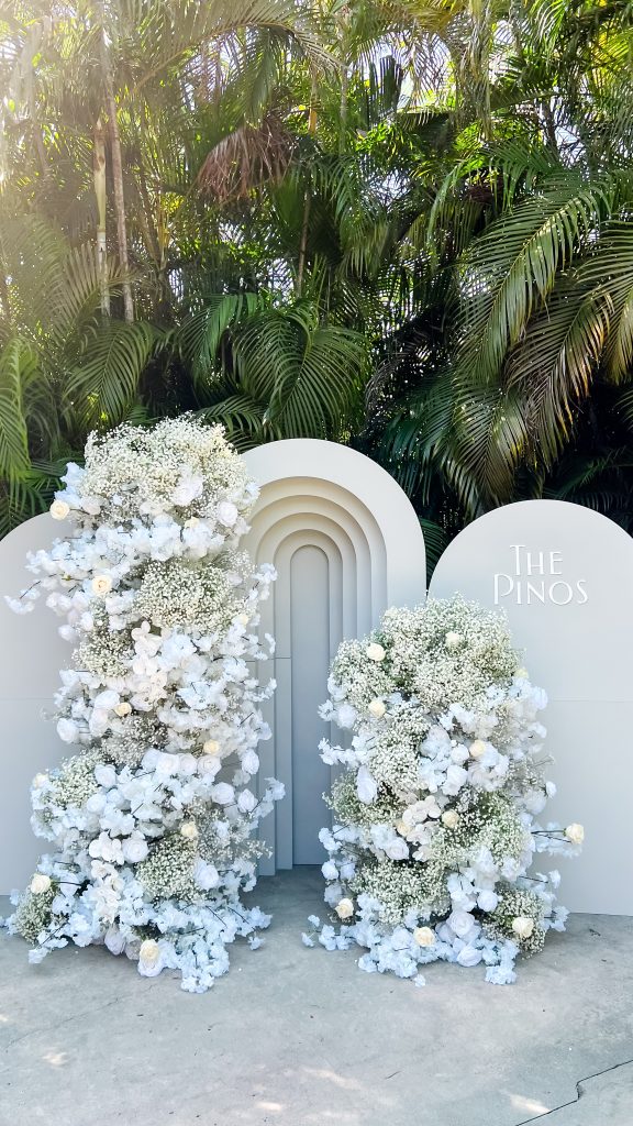 a white archway with flowers and a sign