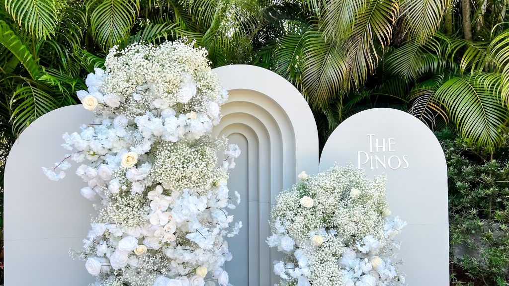 a group of white flowers next to a white arch