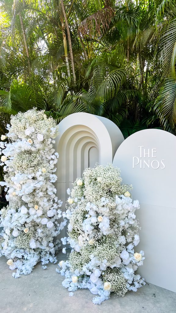 a white arch with flowers and a sign